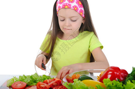 小女孩在桌子上切西红柿白孤立图片