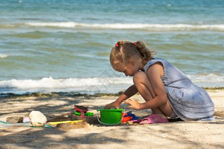 小女孩在海边玩沙子背景