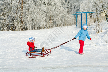 快乐的小女孩和男在冬季雪覆盖院子里图片