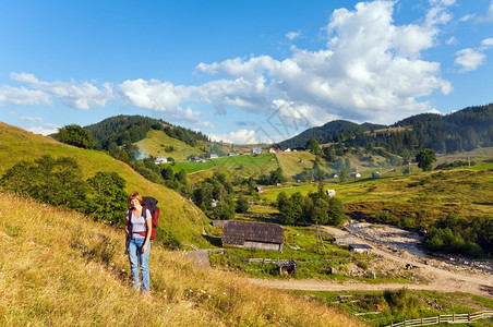 夏季山村景观和前面有三脚架的妇女图片