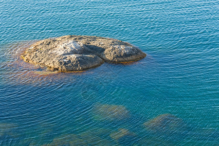 沿海透明蓝水面底部有一些石块图片