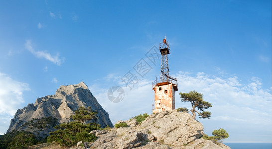 蓝色天空背景SokolrockNovyjSvit保留地克里米亚乌兰的斜坡上有岩石锥形树和旧灯塔Sokolrock乌克兰五针缝合图图片