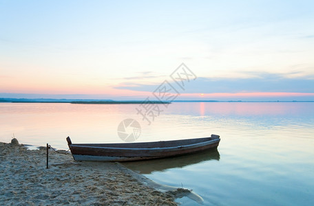 夏季湖岸乌克兰斯维提亚兹附近的日落和老木制渔船图片