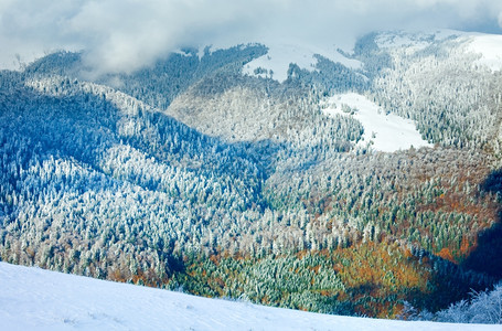 十月的山景第一次冬季雪和去年秋天的多彩叶子在遥远的山边图片