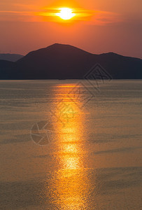 夏季傍晚海岸线有粉红黄日落太阳轨道和地平线上的岛屿图片