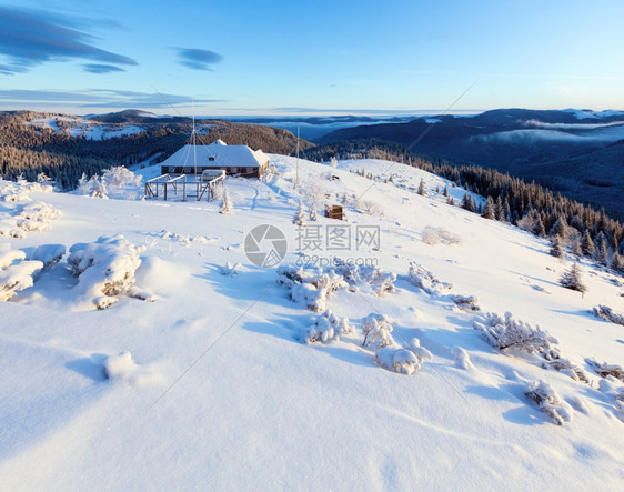 清晨冬季山地风雪覆盖着脊上的树木和房屋图片