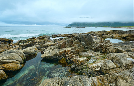 沙滩的夏季阴云和石头中间的游泳池Ramberg挪威Lofoten图片