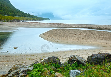 海滩上满是石头的挪威海云般清晨风景图片