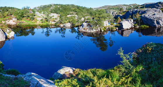 挪威深蓝色小山丘湖有岩石海岸图片