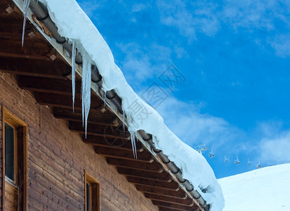 冬季山坡上的木屋顶有雪和冰块背景图片