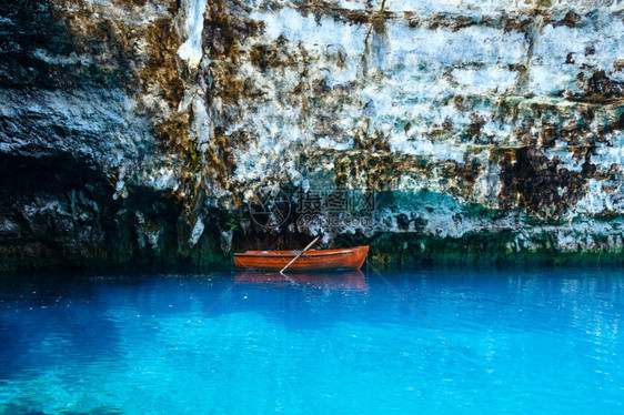 在地下湖表面Melissani湖Kefalonia希腊陡峭岩石附近的木质船图片