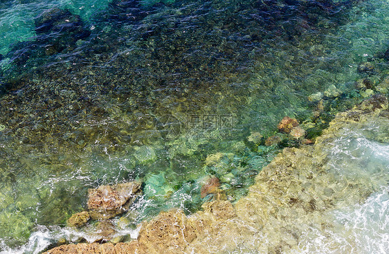 浅的海水表面底部有石块从上面看自然背景图片