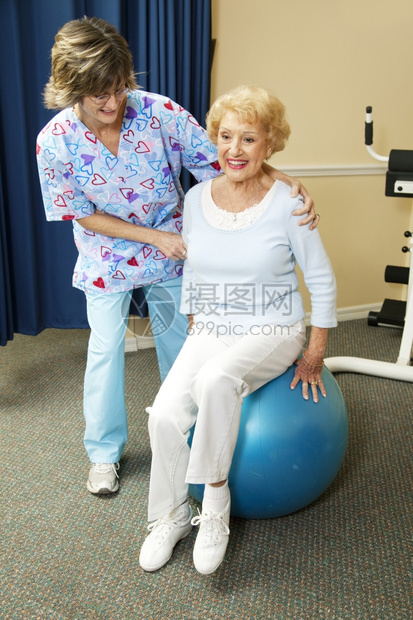理疗师帮助一位高龄女参加一个Pilates球赛的锻炼图片