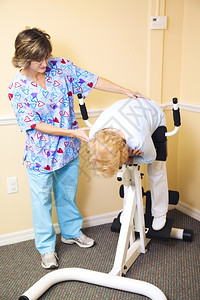 脊椎按摩师办公室的理疗帮助一位年长的女士伸展脊椎图片