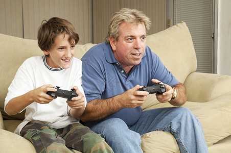 父亲和儿子叔侄在家里玩电游戏图片