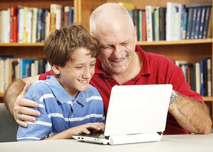 图书馆的父亲和儿子使用一台小的网书电脑图片