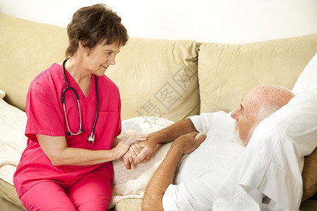慈悲的家庭保健护士握着一位年长病人的手图片