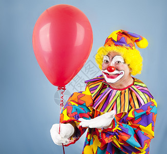 友善的小丑给你一个明亮的红气球图片
