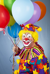 在蓝背景面前带着气球的快乐小丑图片