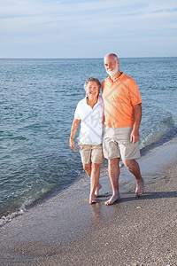 快乐的老年情侣在海滩上漫步图片