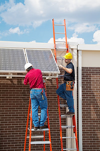 两个工人在一栋楼的侧面安装太阳能电池板垂直与文字空间图片