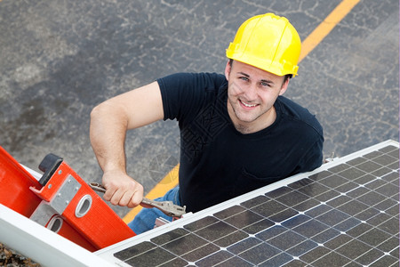 年轻电工在梯子上安装太阳能电池板图片