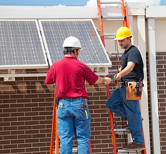 两个电工在一栋大楼的侧安装太阳能电池板图片