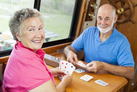 快乐的退休夫妇玩牌在他们的汽车家里图片