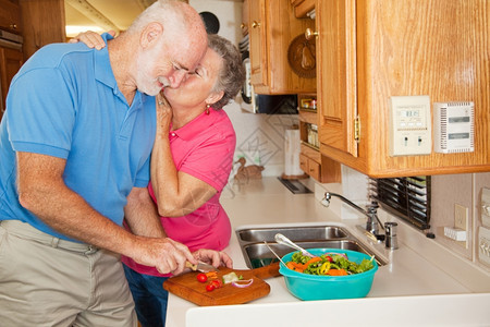 老人在他们的房车厨里帮老婆的人得到一个吻的奖赏图片
