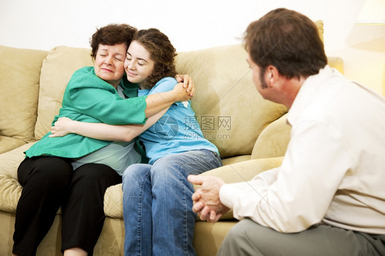 母亲和女儿与治疗师在家庭咨询期间拥抱图片