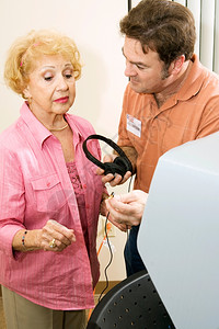 选举志愿者提供耳机协助一名老年妇女投票图片