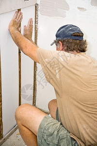 承包商在其正更换的墙段内安装泡沫隔热置图片