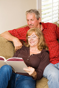 漂亮的成熟夫妇在家沙发上放松读书图片
