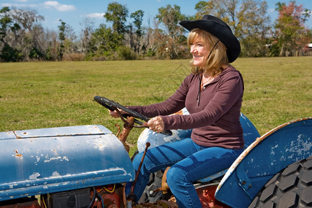 美丽的成熟女人驾驶拖拉机在农场图片