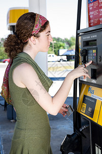 无卡支付年轻妇女用她的自动取款机卡支付汽油费用背景