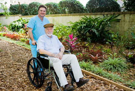 护理员带一个老人去花园散步图片