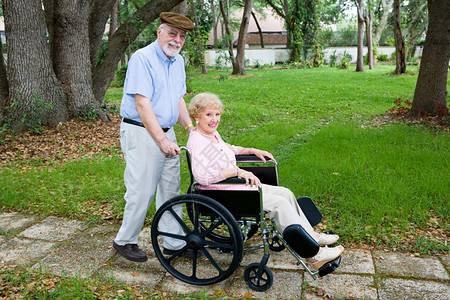 老年残疾妇女被其爱人的丈夫用轮椅推过公园图片