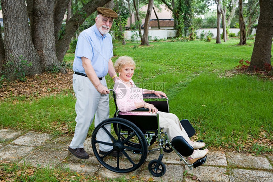 老年残疾妇女被其爱人的丈夫用轮椅推过公园图片