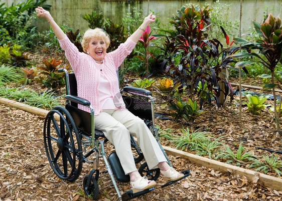 坐在轮椅上的美丽高级女士太兴了因为她战胜自己的健康问题图片