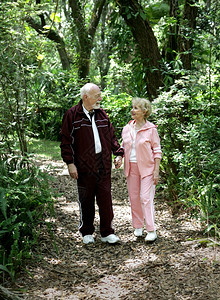 一个有吸引力的老夫妇手牵在公园里漫步图片