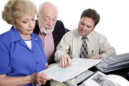 一对年长的夫妇和他们会计一起翻阅了税册孤立在白色上图片