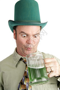 圣帕特里克日的男子带着预感在杯绿色啤酒中寻找图片