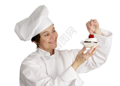 一个糕点厨师把草莓放在一个芝士蛋糕饼的顶部白孤立图片