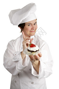 一个拿着草莓芝士蛋糕的厨师摇着她手指不图片