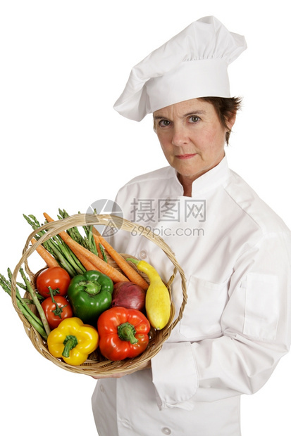 一位女厨师拿着一篮子蔬菜表现严肃她认真对待营养问题图片