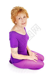 一位美丽的70岁女人穿着运动服跪在地上白色背景图片