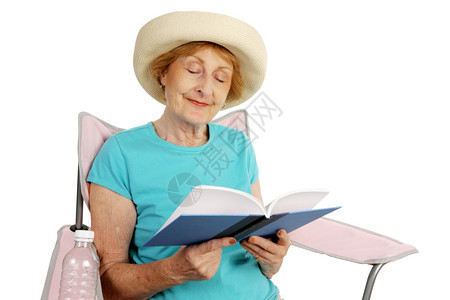 一位漂亮的女士躺在沙滩椅上看书孤立的白种人图片