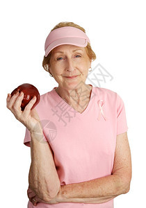 一位穿着粉红色衣服的老年妇女穿着红苹果做健康点心图片
