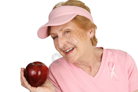 一位身着乳癌意识的老妇人拿着一个明亮的红苹果图片