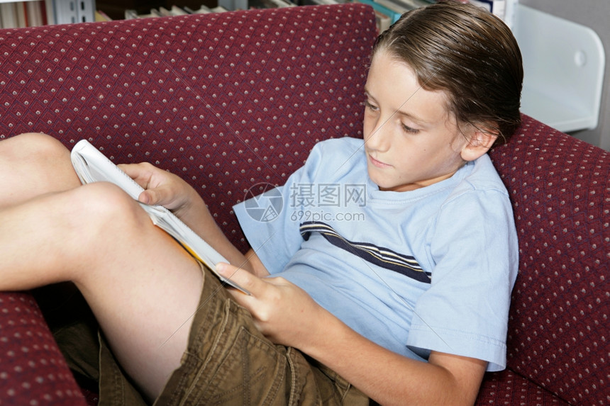 在学校图书馆读杂志的年轻男学生图片